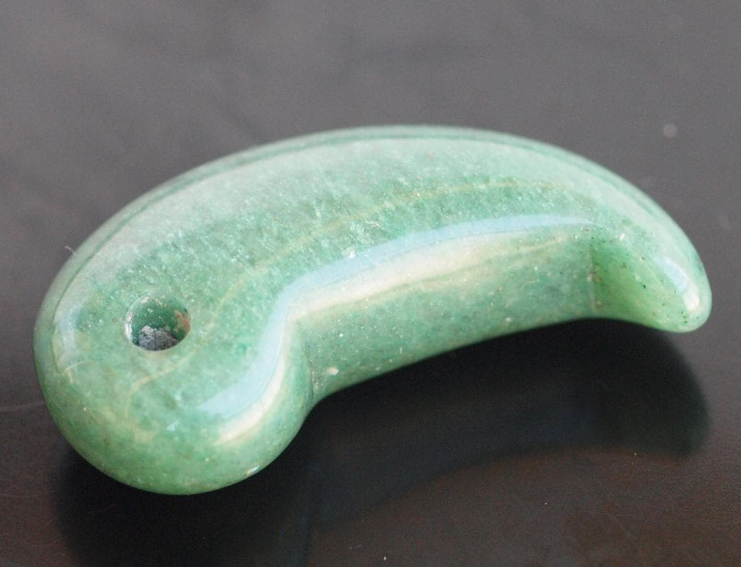 光にかざすと薄緑の細い帯状紋が出現、頭・胴の間には沈線、ずんぐり形の勾玉　沖縄の